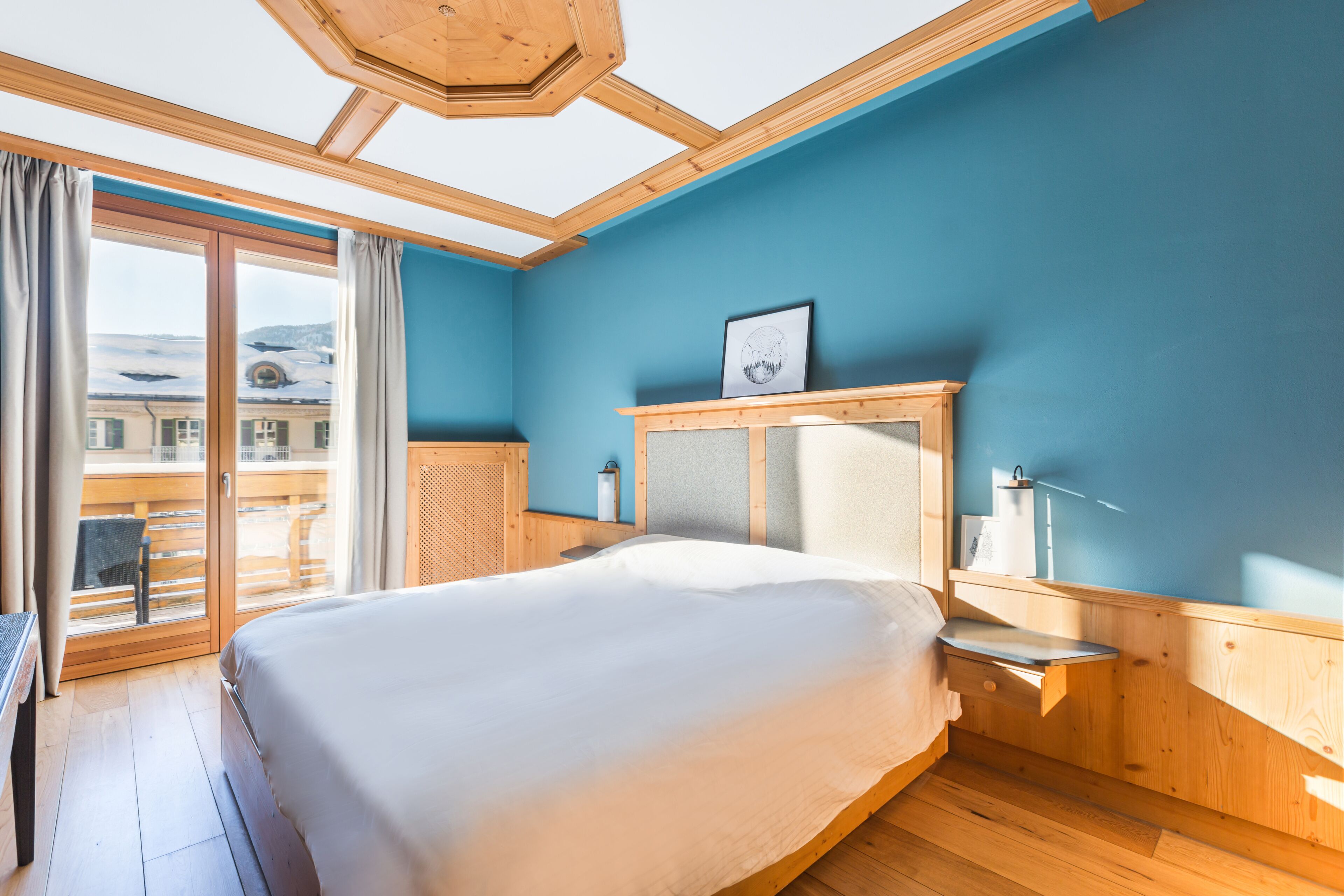 Un dormitorio con una cama grande, cabecera de madera, una mesita de noche y vistas a un balcón.