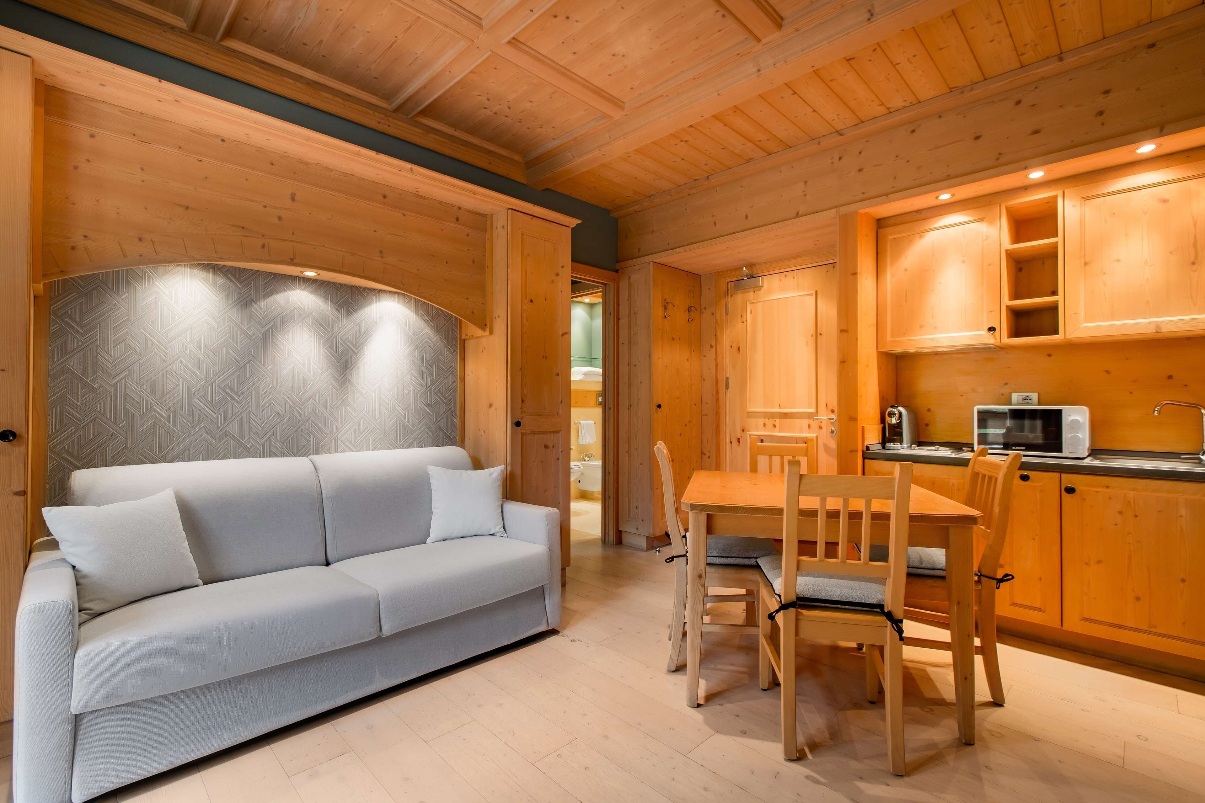 A modern interior with a sofa, dining table, wooden cabinets, and a microwave.
