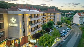 A hotel with multiple balconies, outdoor seating, and a parking area. - Hotel Los Arces (Arnuero)