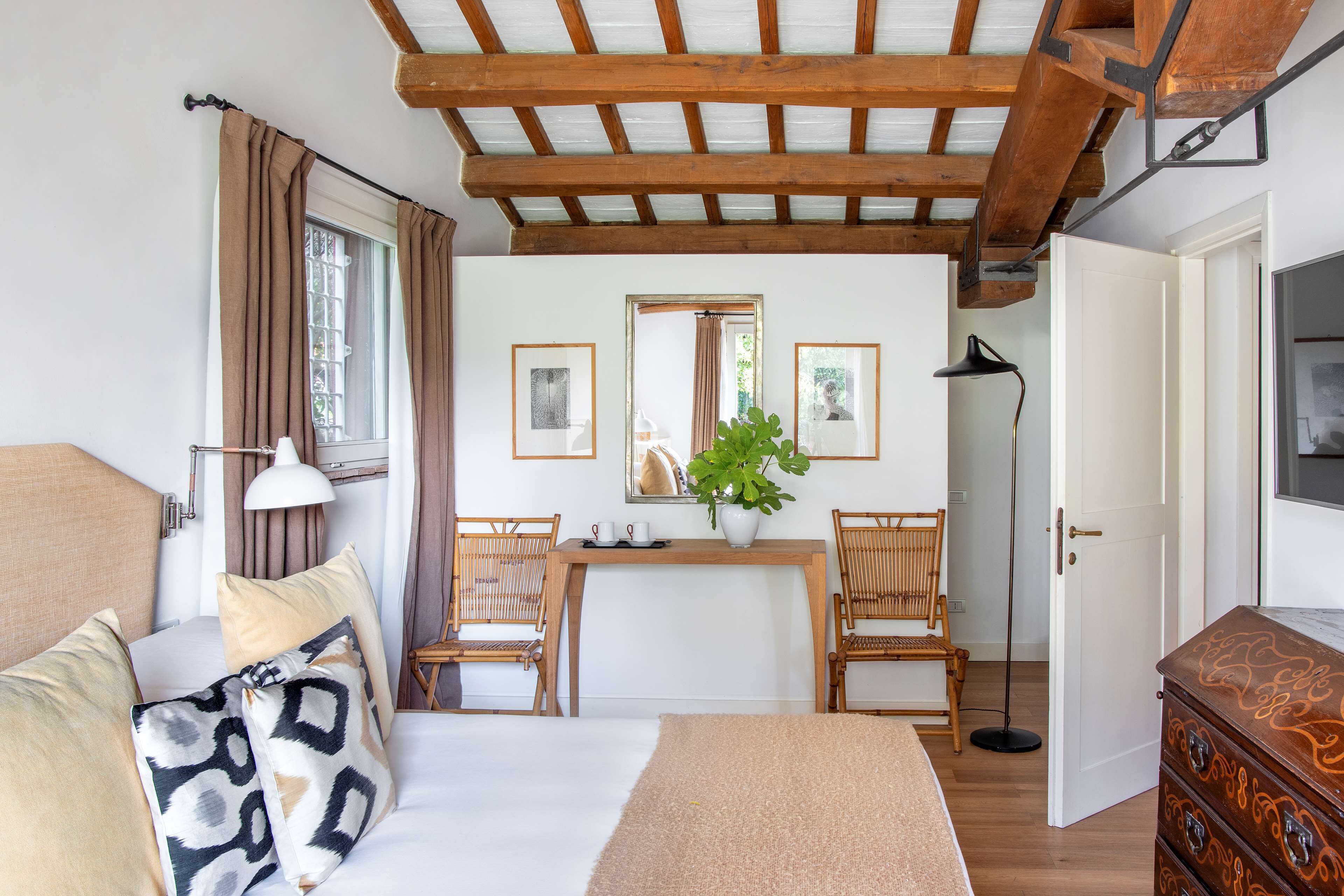 A bedroom with a bed, bedside table, lamp, and a dresser.