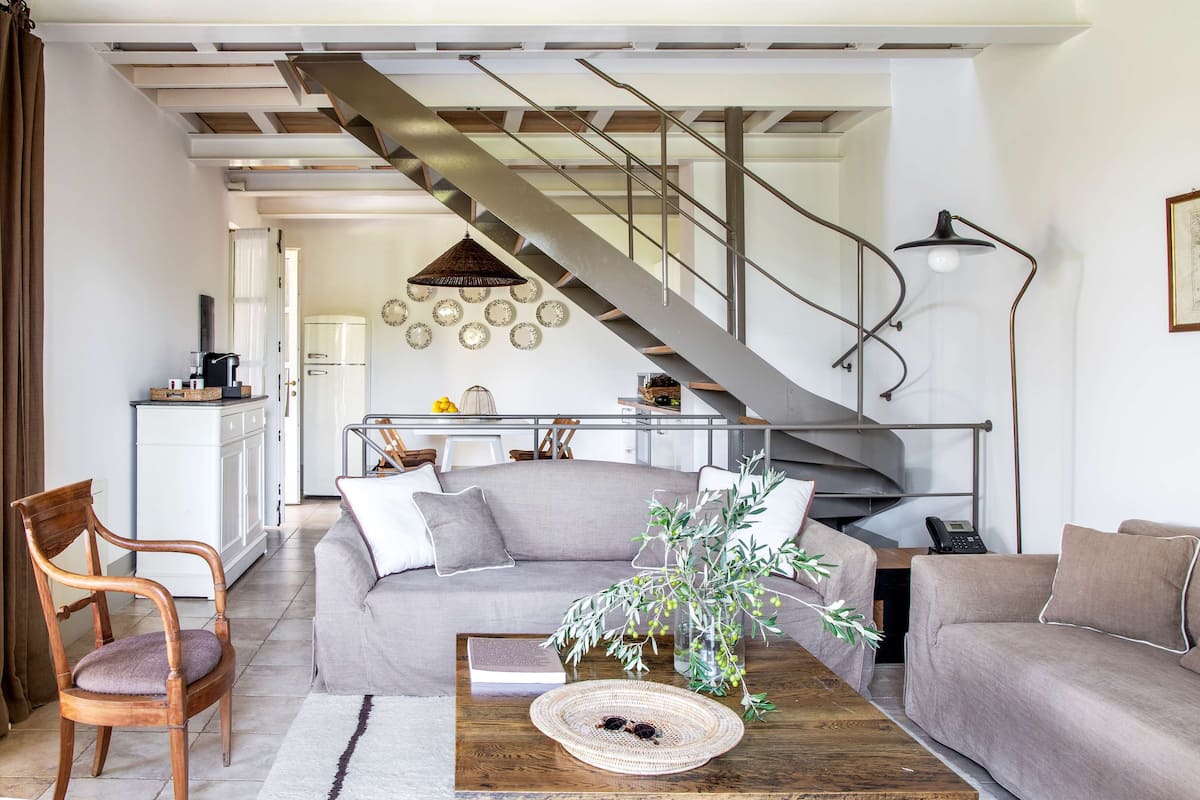 A modern living room with a staircase, a sofa set, a coffee table, and a dining area.