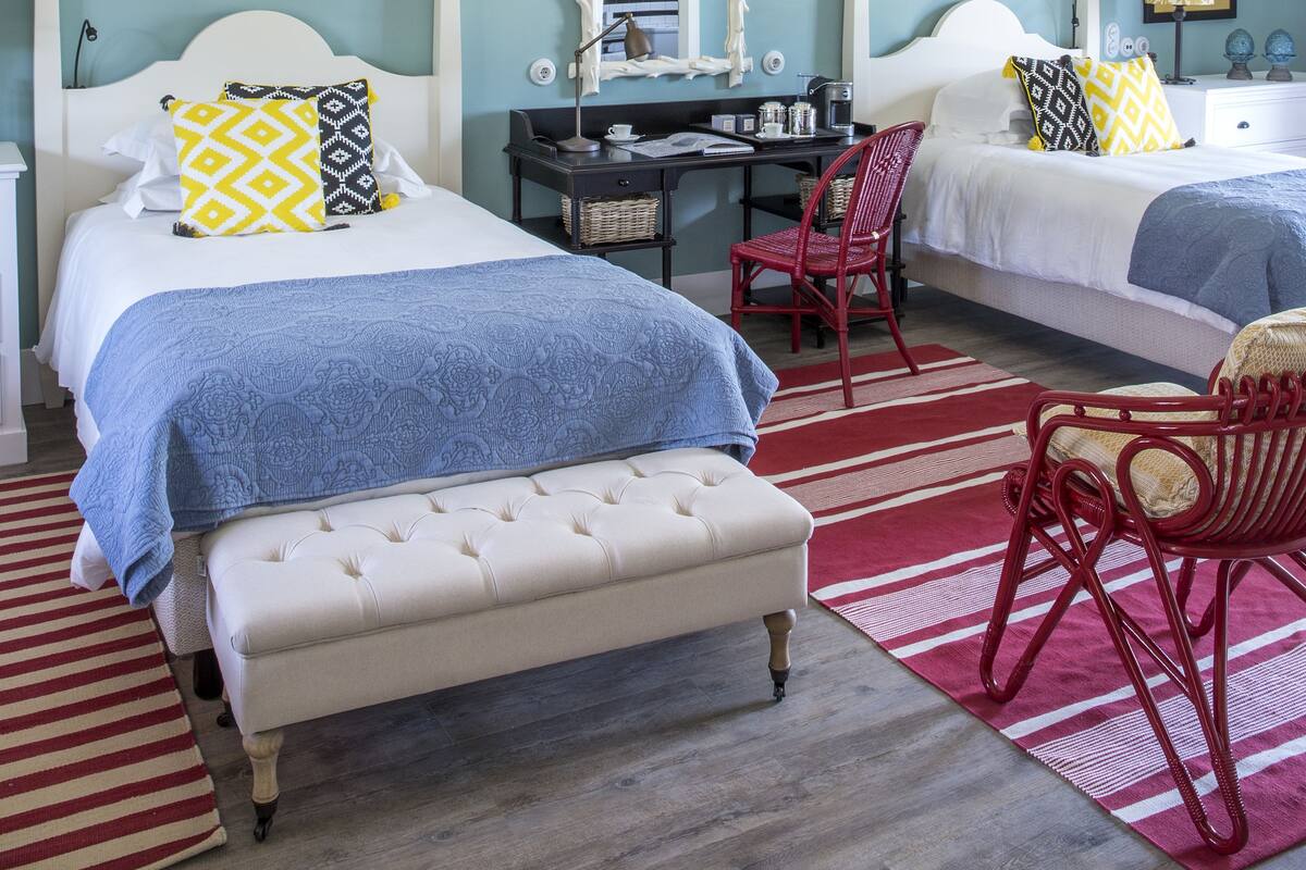 A hotel room with two beds, a desk, and a chair.
