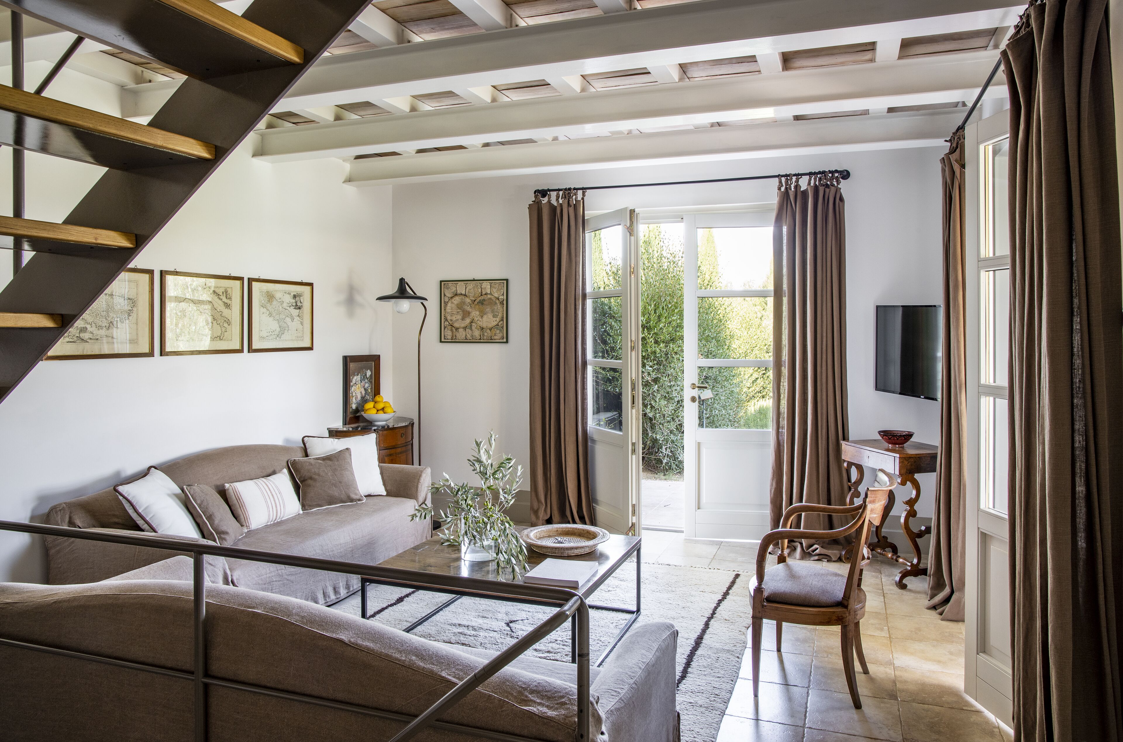 Ein modernes Wohnzimmer mit Sofa, Couchtisch und Sessel. Eine Treppe führt zu einer oberen Ebene.