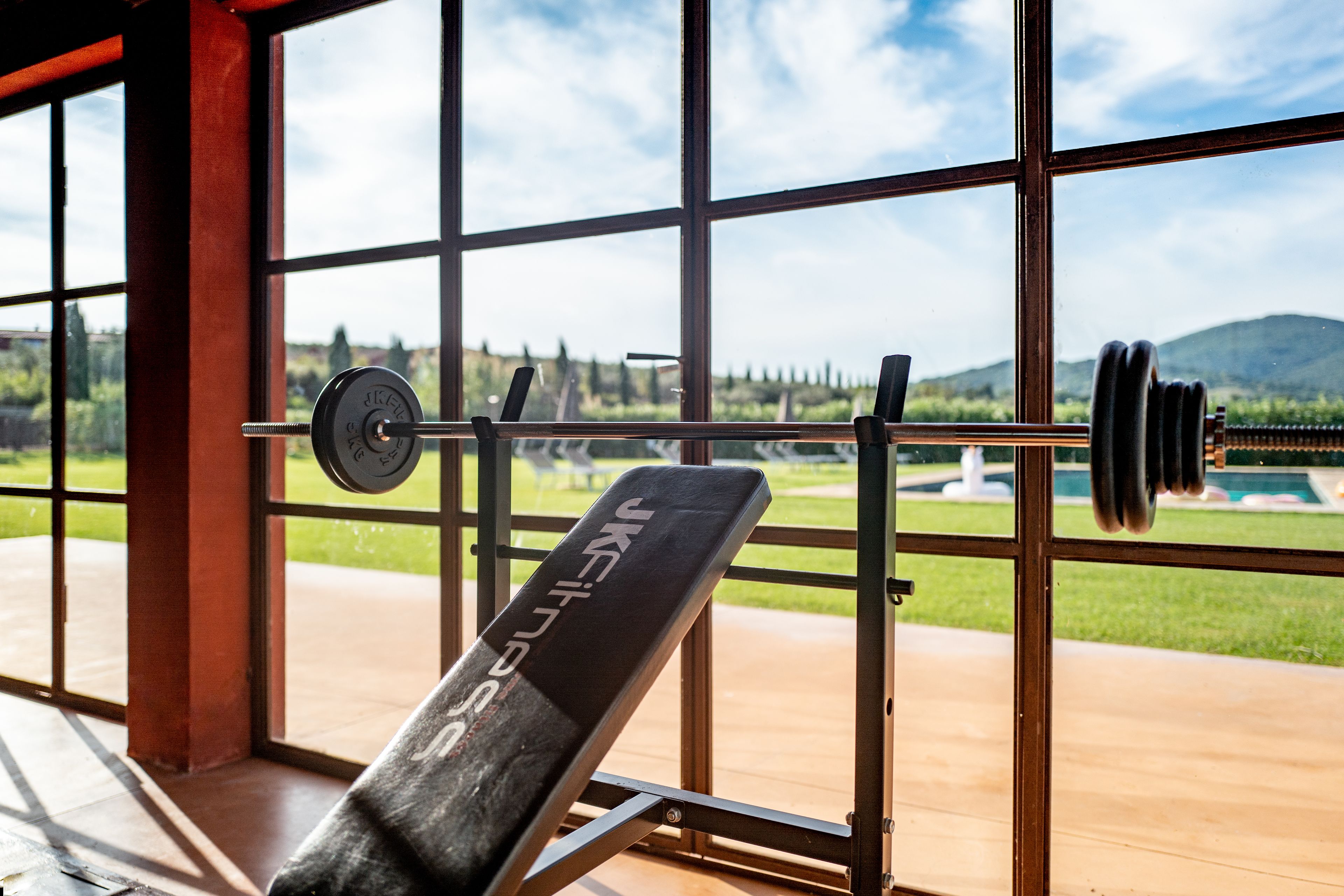 A gym with a weightlifting bench and a barbell rack.