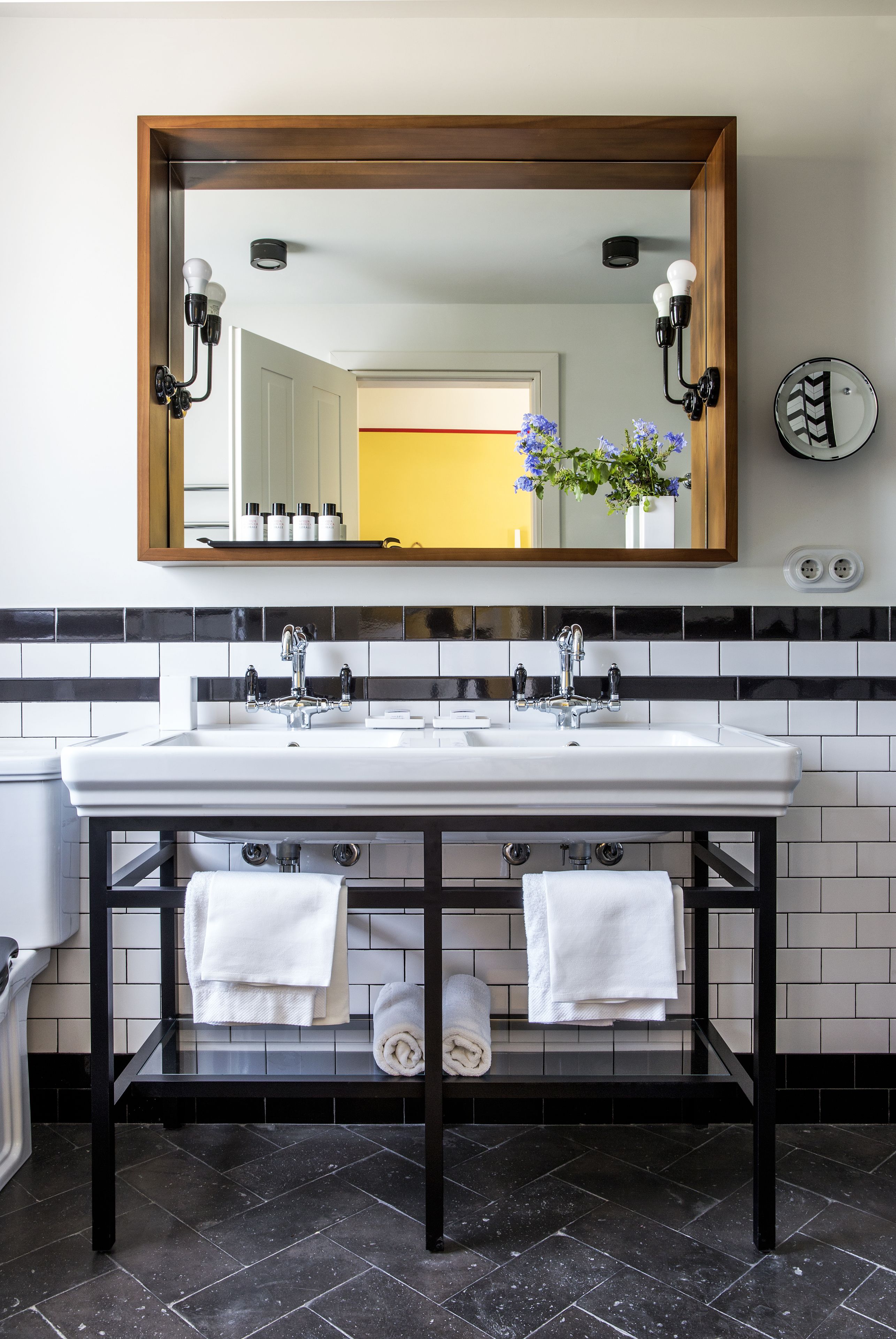 A bathroom with a double sink, black and white tiled backsplash, and a mirror above the sink.