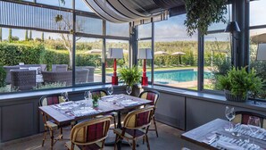 An outdoor dining area with wicker furniture, a pool view, and potted plants. - Resort Locanda Rossa (Capalbio)