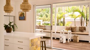 A modern kitchen with white cabinetry, a central island, and a dining area with a wooden table and chairs. - Atlantic Byron Bay (Byron Bay)