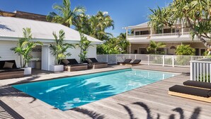 A swimming pool with wooden deck, lounge chairs, and palm trees. - Atlantic Byron Bay (Byron Bay)
