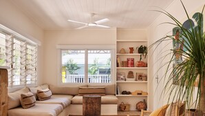 A cozy living room with a sofa, a wooden chair, a bookshelf, and a large window. - Atlantic Byron Bay (Byron Bay)