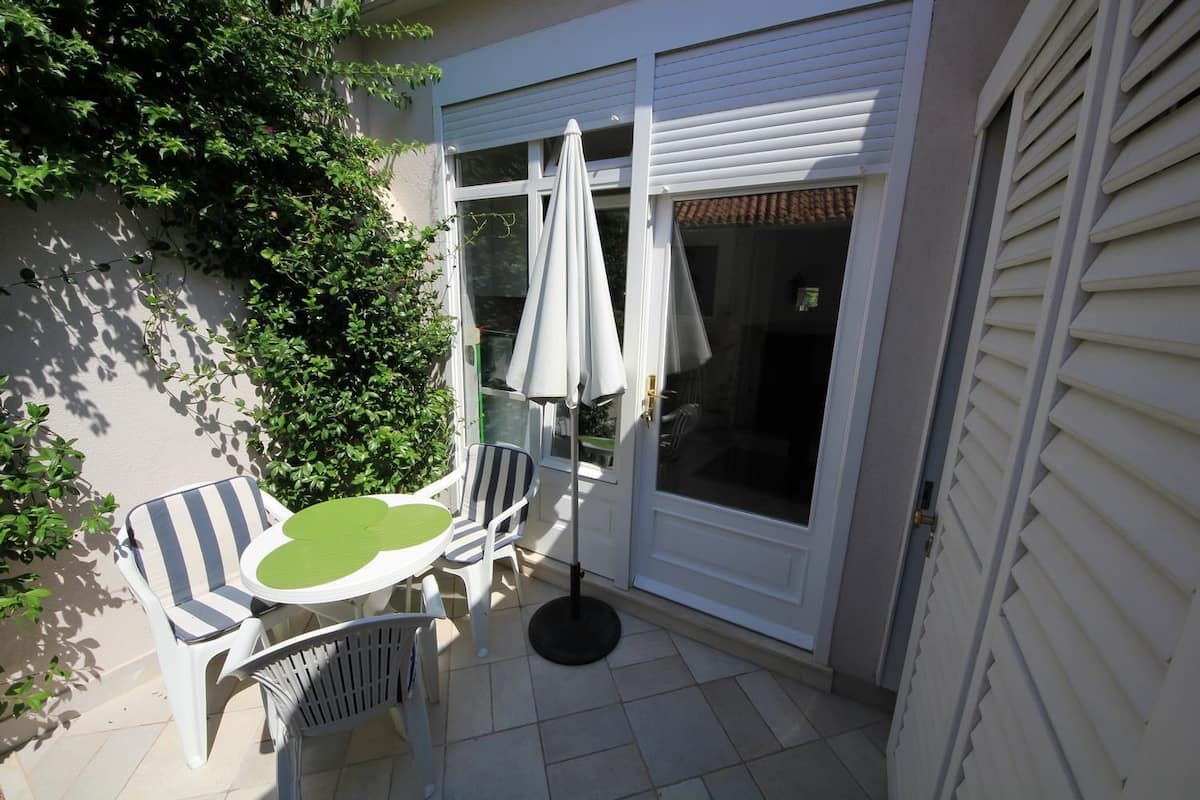 A patio with a table and chairs, a white umbrella, and a sliding glass door.