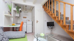 A modern living room with a glass coffee table, a sofa, a TV, and a staircase. - Dubrovnik Center Apartments (Dubrovnik)