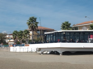 A bus station with a covered waiting area and a building in the background. - Hotel San Carlo (Terracina)