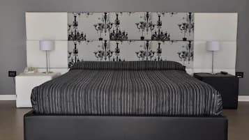 Una camera da letto moderna con un letto grande, una testiera bianca con motivo floreale nero, due comodini con lampade e un comodino nero.