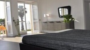 A bedroom with a bed, a mirror, a potted plant, and a view through an open door. - Hotel San Carlo (Terracina)