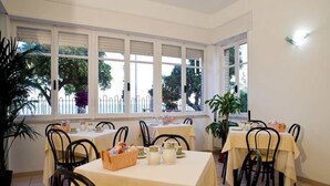 A dining area with tables set for breakfast, featuring wicker chairs and white tablecloths. - Hotel San Carlo (Terracina)