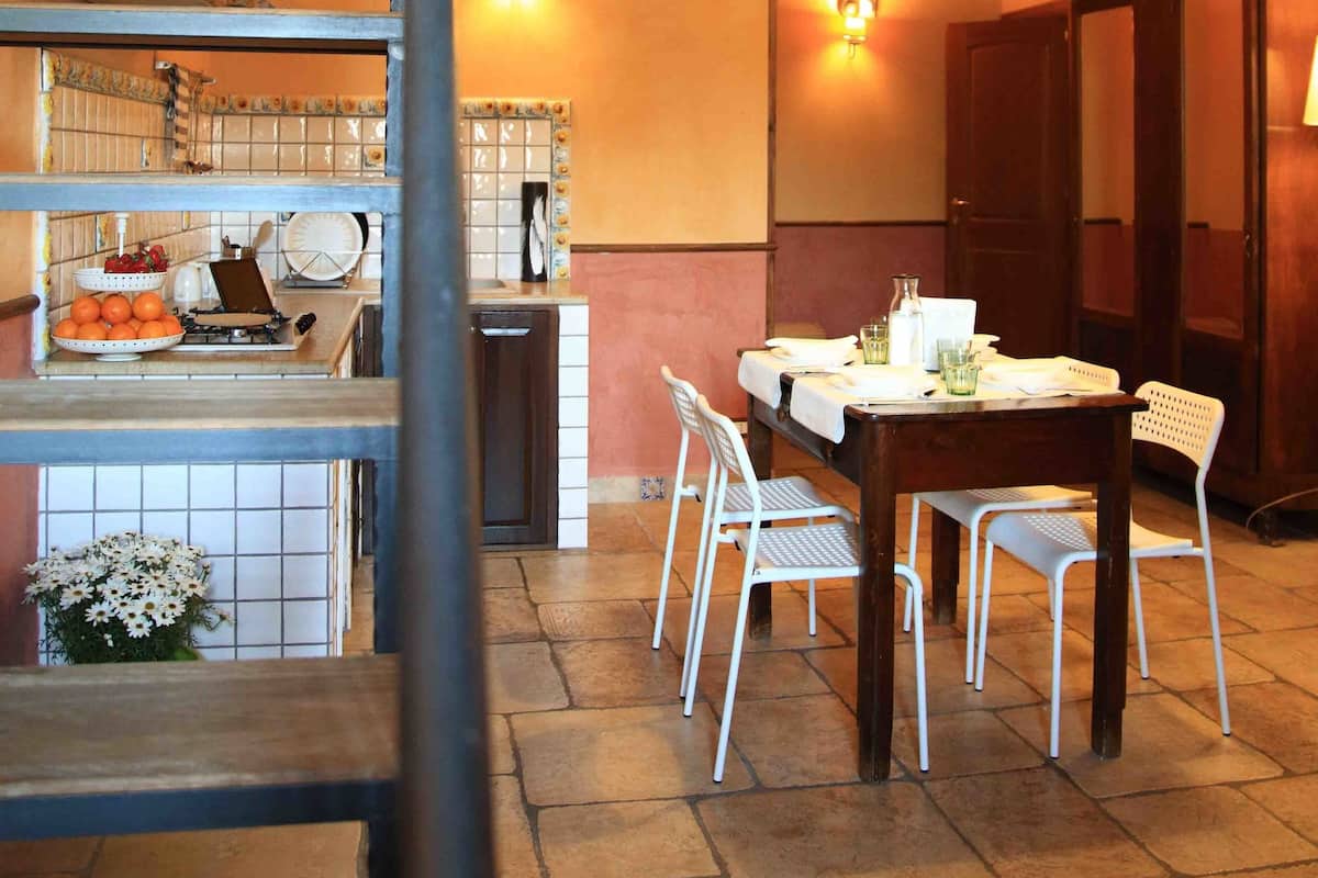 A dining area with a table and chairs, a staircase, and a hanging plant.