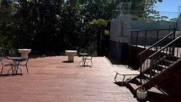 Terraza en la azotea con mobiliario exterior, una escalera y follaje circundante.