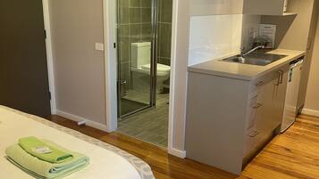 Ein kleines Hotelzimmer mit Bett, einer Küchenzeile, einer Dusche und einem WC.