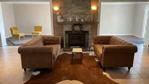 A living room with two brown leather sofas, a stone fireplace, and a cowhide rug.