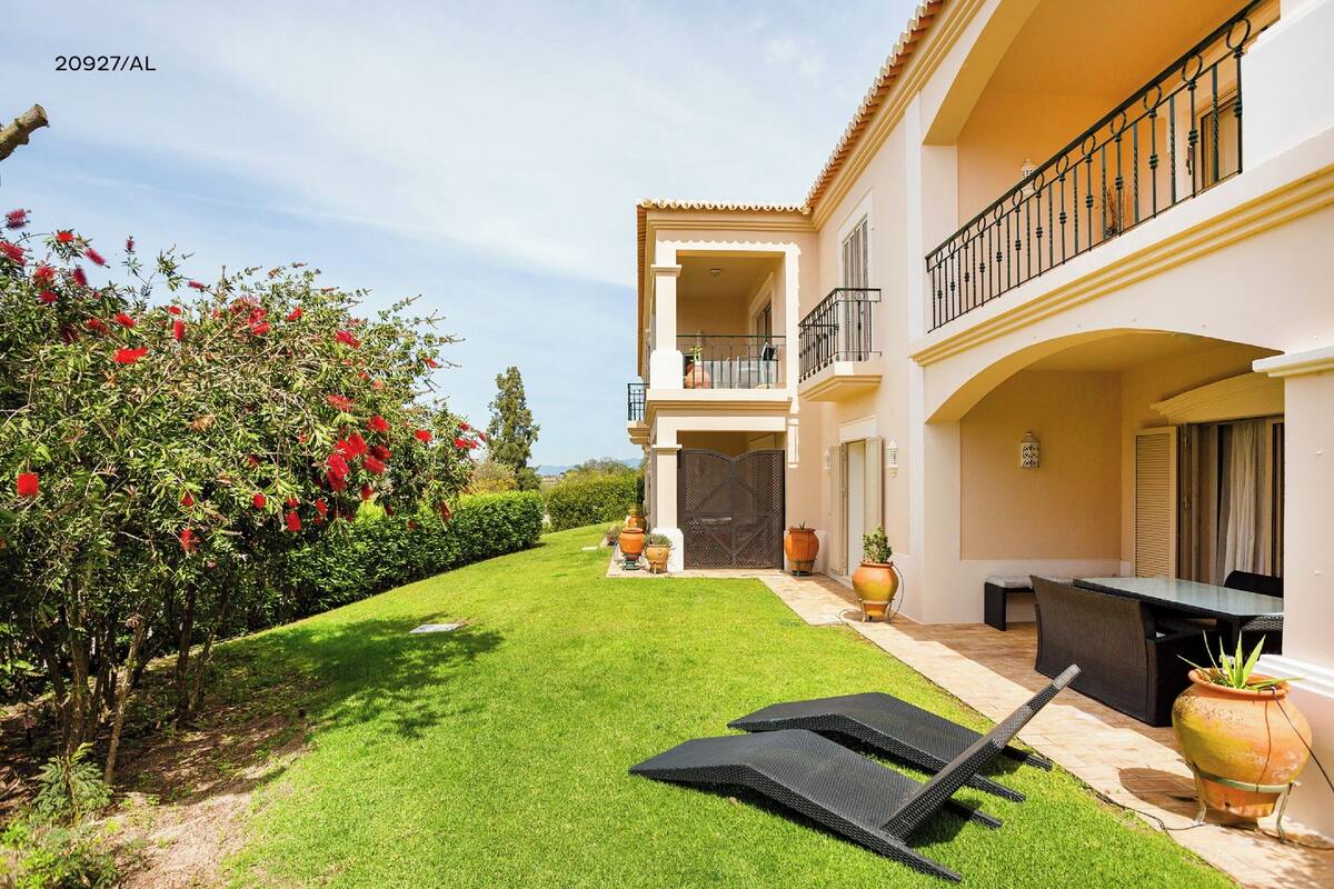 A two-story house with a balcony, outdoor seating, and a well-maintained garden.