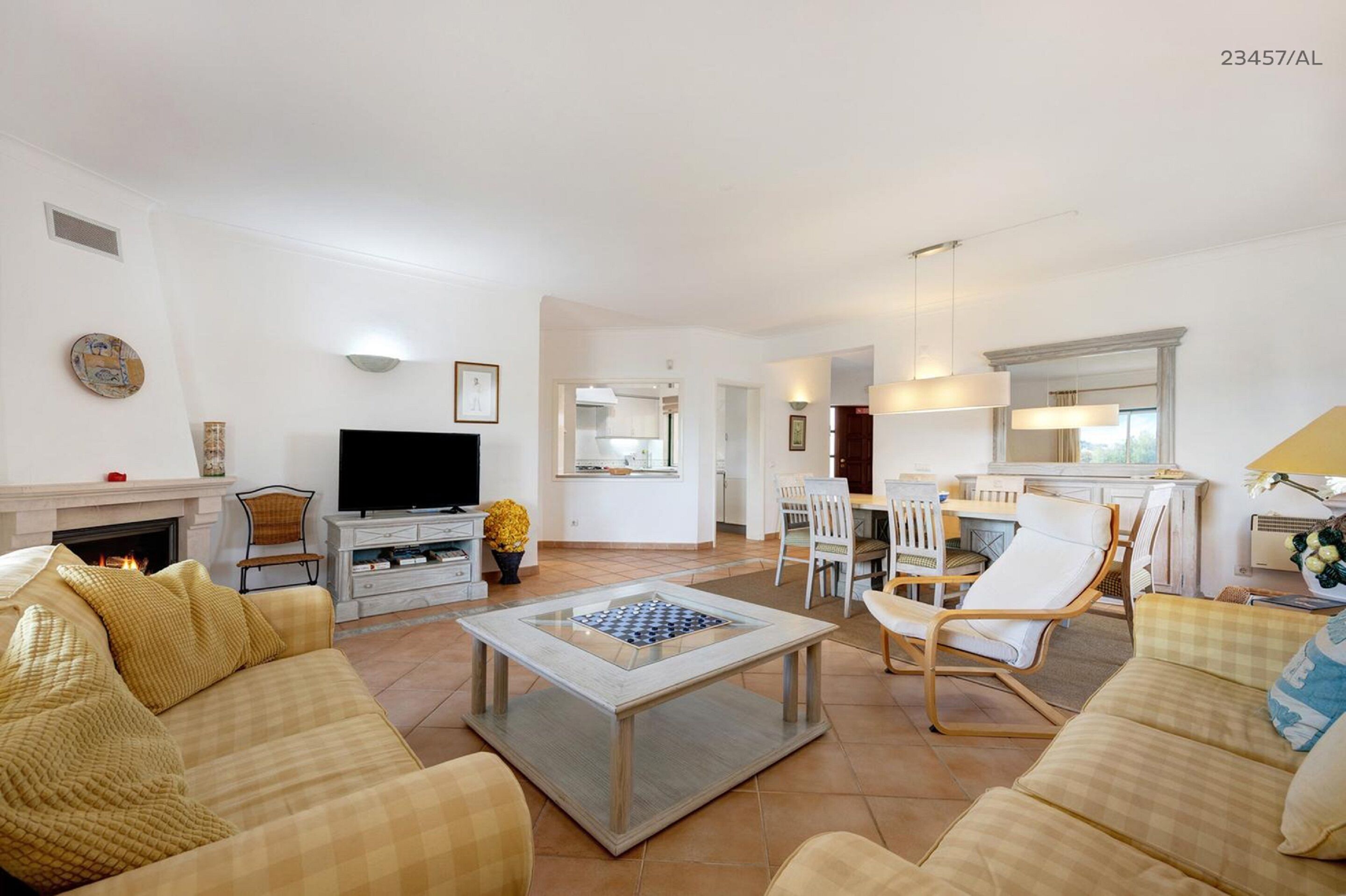 A spacious living room with a fireplace, a television, and a dining area with chairs and a table.