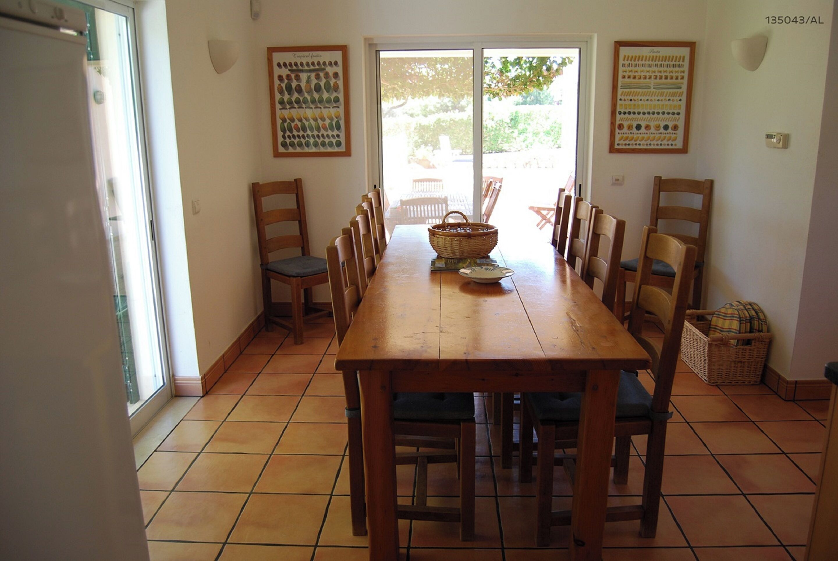 Un coin repas avec une table et des chaises en bois, un panier et une porte donnant sur l’extérieur.