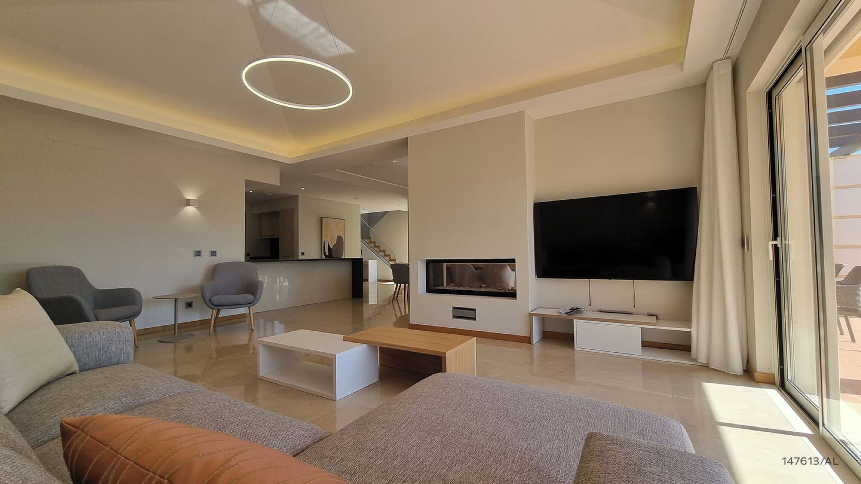 Un salon moderne doté d’un grand téléviseur à écran plat, d’un canapé, d’une table basse et d’une cheminée.