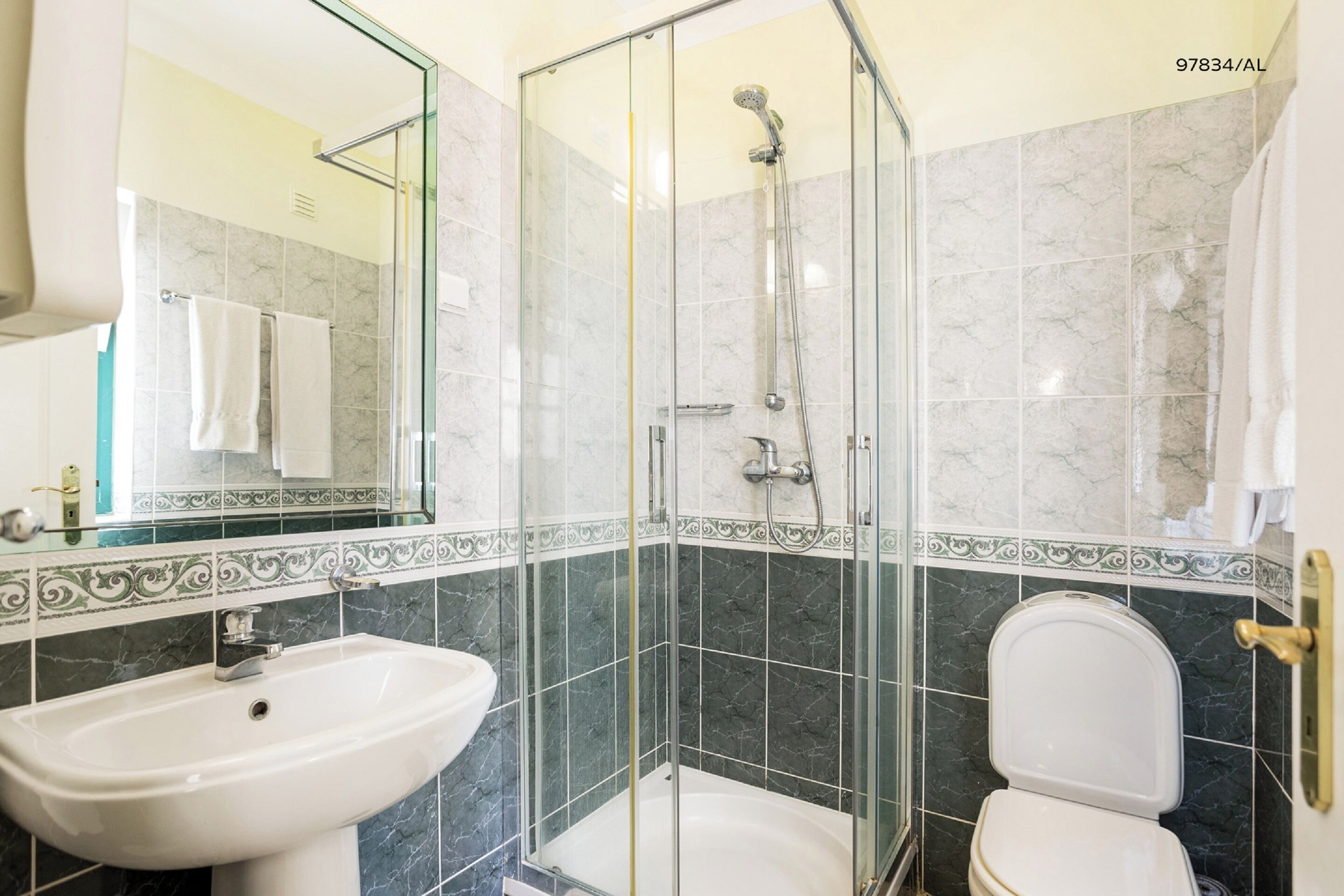 A bathroom with a glass-enclosed shower, a sink, and a toilet.