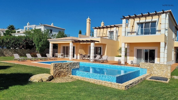 Une villa moderne dotée d’une piscine, d’un espace extérieur aménagé et d’un mur en pierre.