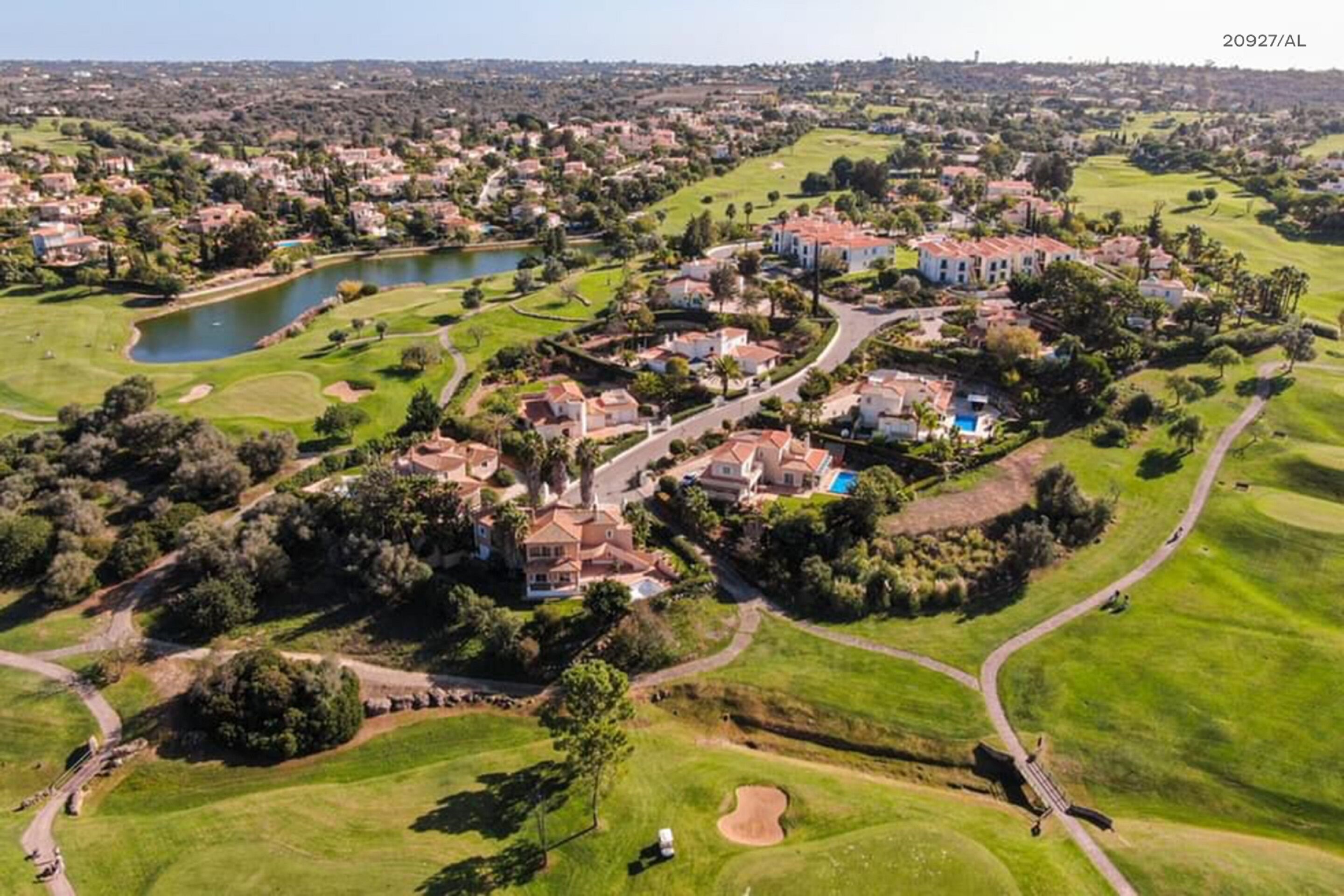 An aerial view of a golf course with houses and a lake.