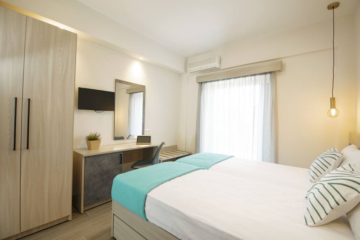 Una habitación de hotel moderna con cama, escritorio y armario.