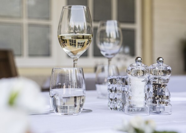 Una mesa con varias copas de vino y saleros y pimenteros.