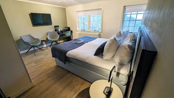 A bedroom with a bed, a desk, a chair, and a round table.