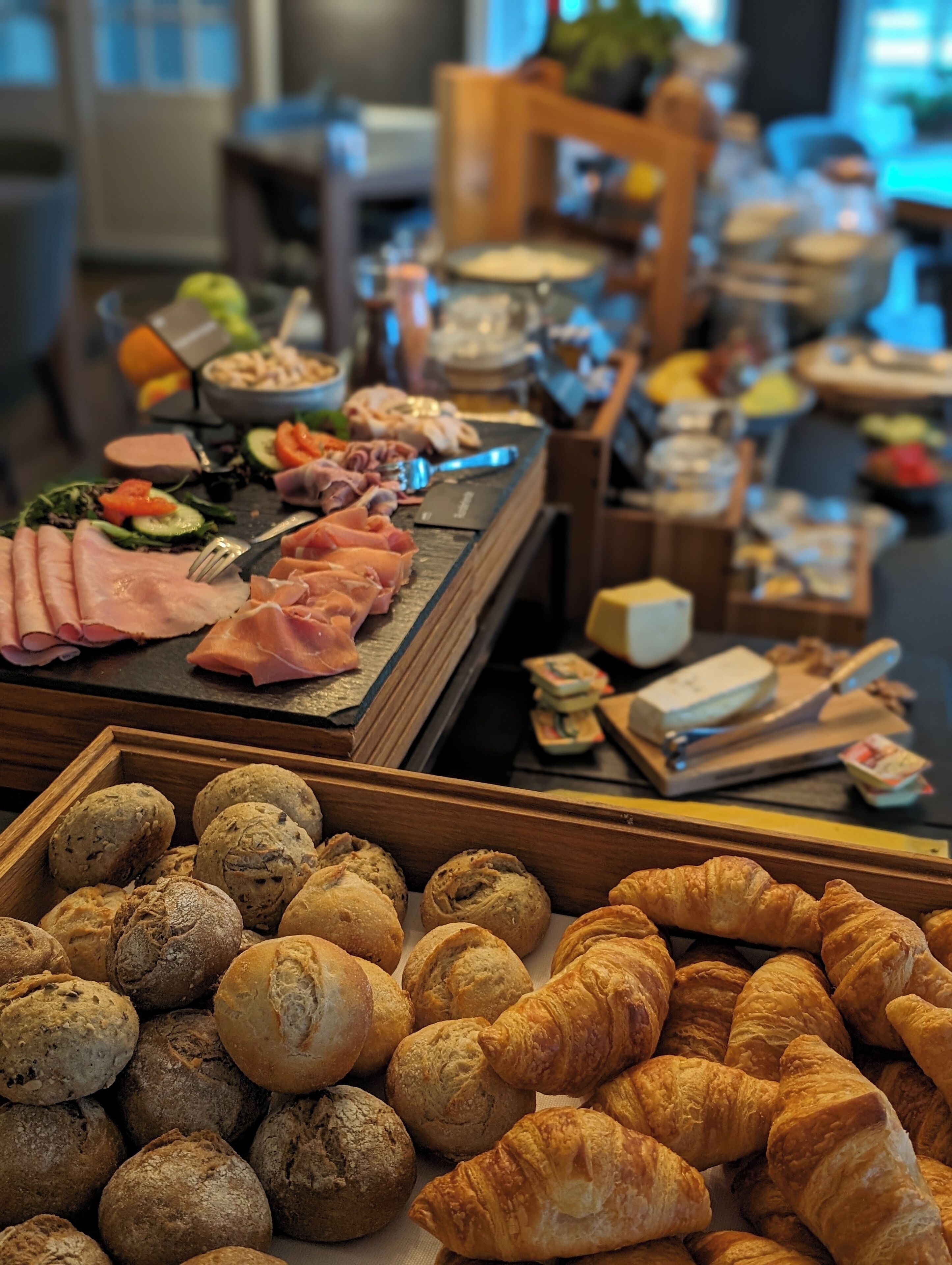 Un bufé con diversos alimentos, incluyendo carnes, verduras, panadería y pasteles.