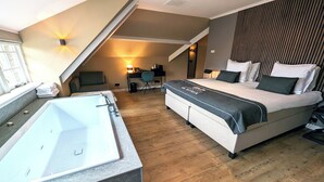Un dormitorio moderno con una cama grande, un baño separado con bañera y una zona de escritorio.