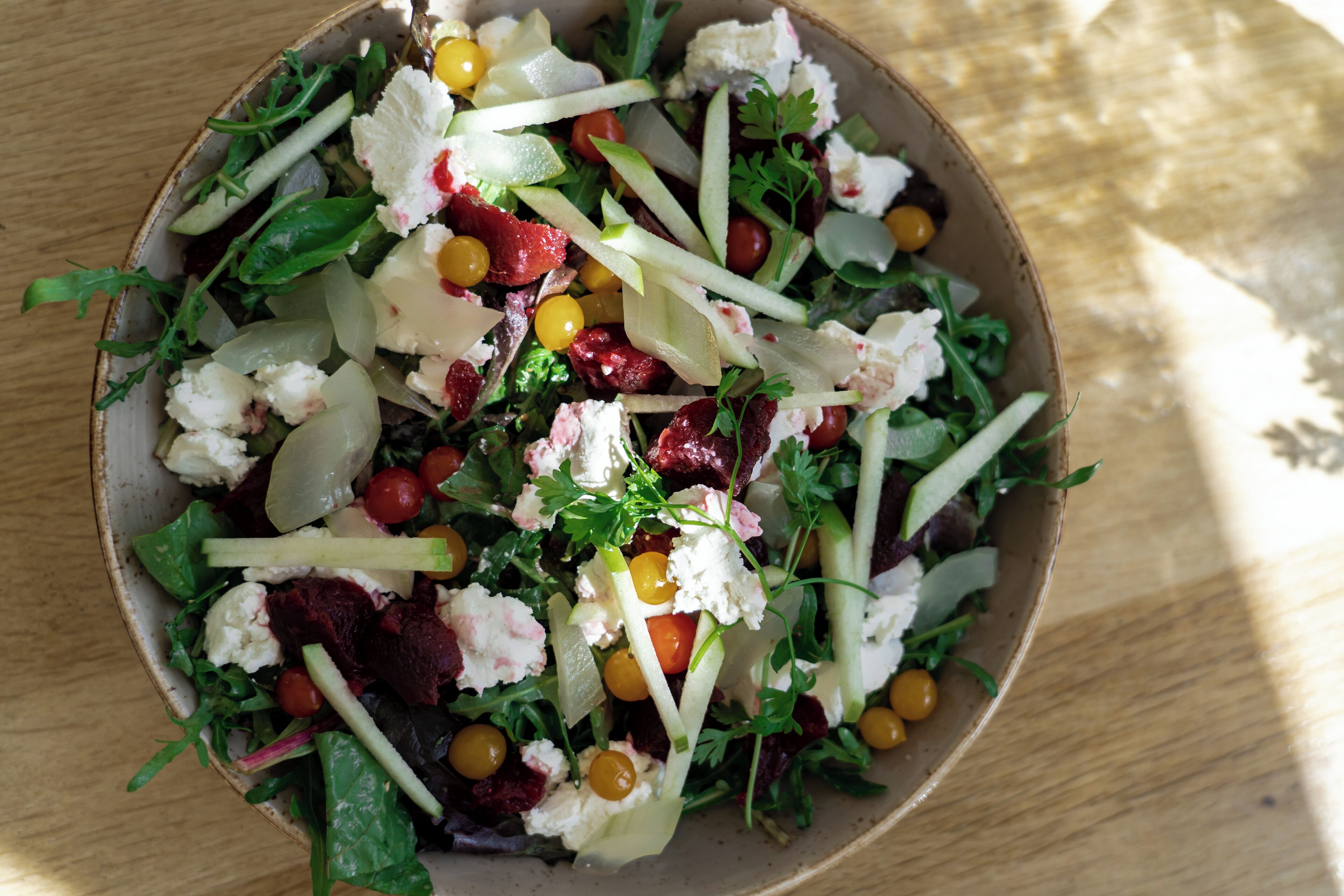 A bowl of salad with various vegetables and cheese.