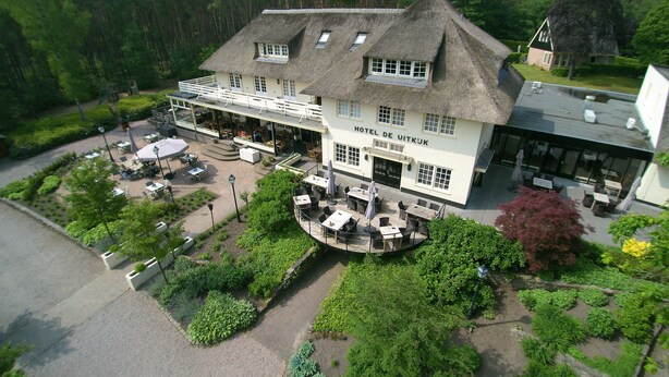 Un hotel con techo de paja, zona de estar exterior y jardín.