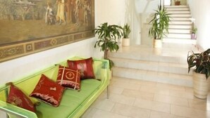 Un vestíbulo con un sofá verde, un mural grande y una escalera que conduce a un nivel superior.