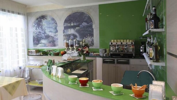 Una cocina moderna con encimera verde, diferentes electrodomésticos y un comedor con mesa y sillas.