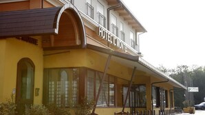 Un hotel con fachada amarilla, ventanas arqueadas y un balcón con barandilla.