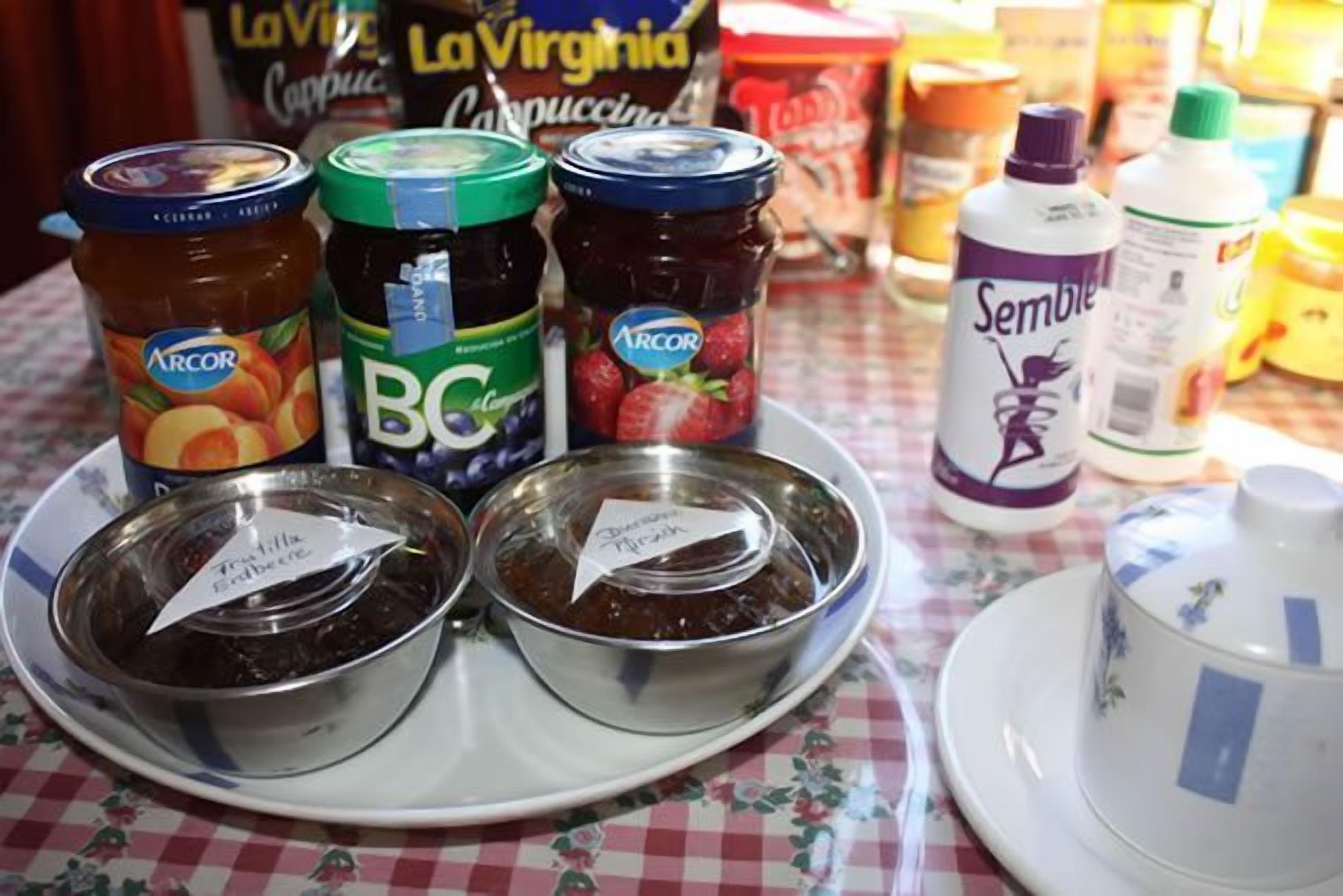 A table with jars of preserves and a bottle of Sembler.