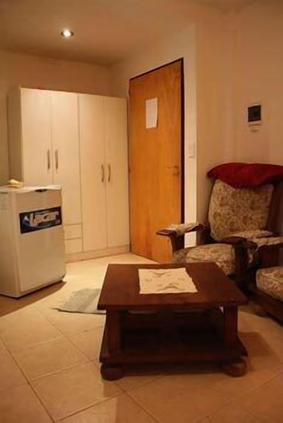 A compact living space with a kitchenette, a wooden table, and a sofa.