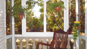 A wooden chair with a red cushion on a porch with a white balustrade. - La Casona de Susana (Colon)