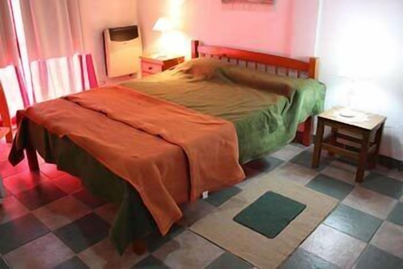 A bedroom with a bed, a nightstand, a lamp, and a small table.