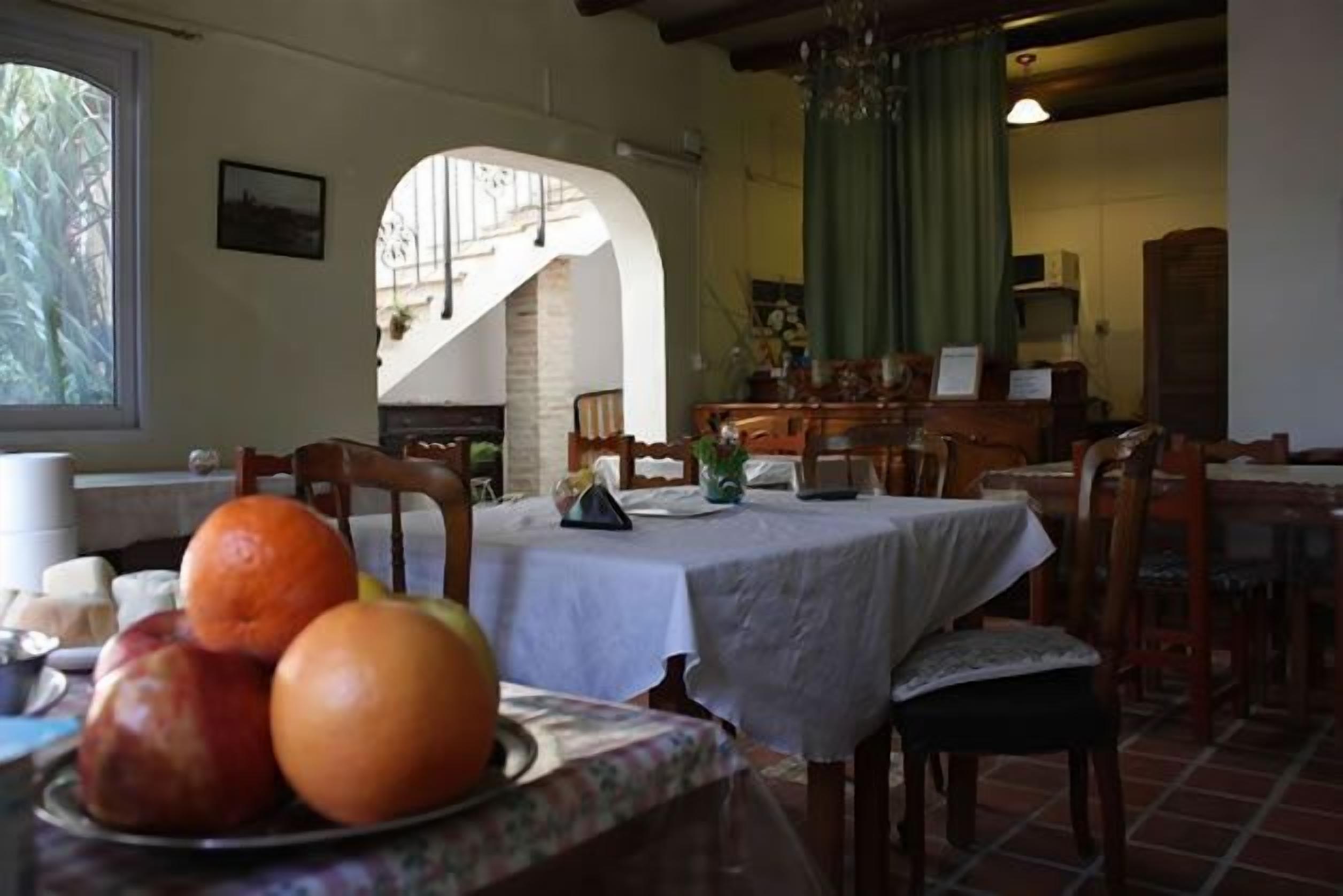 Zona pranzo con tavolo apparecchiato per due, un piatto di frutta e una scala che conduce a un livello superiore.
