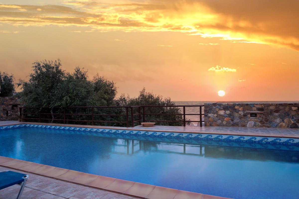 A swimming pool with a stone wall and a wooden deck.