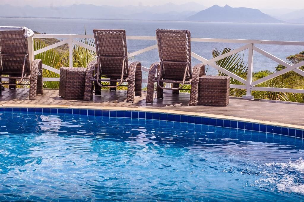 A poolside area with wicker chairs and a view of the sea.