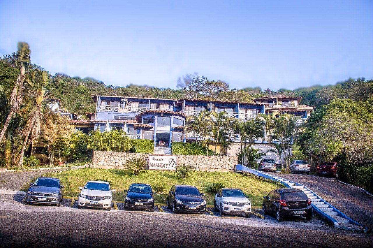 Un hotel con diversi edifici, un muro in pietra e auto parcheggiate.