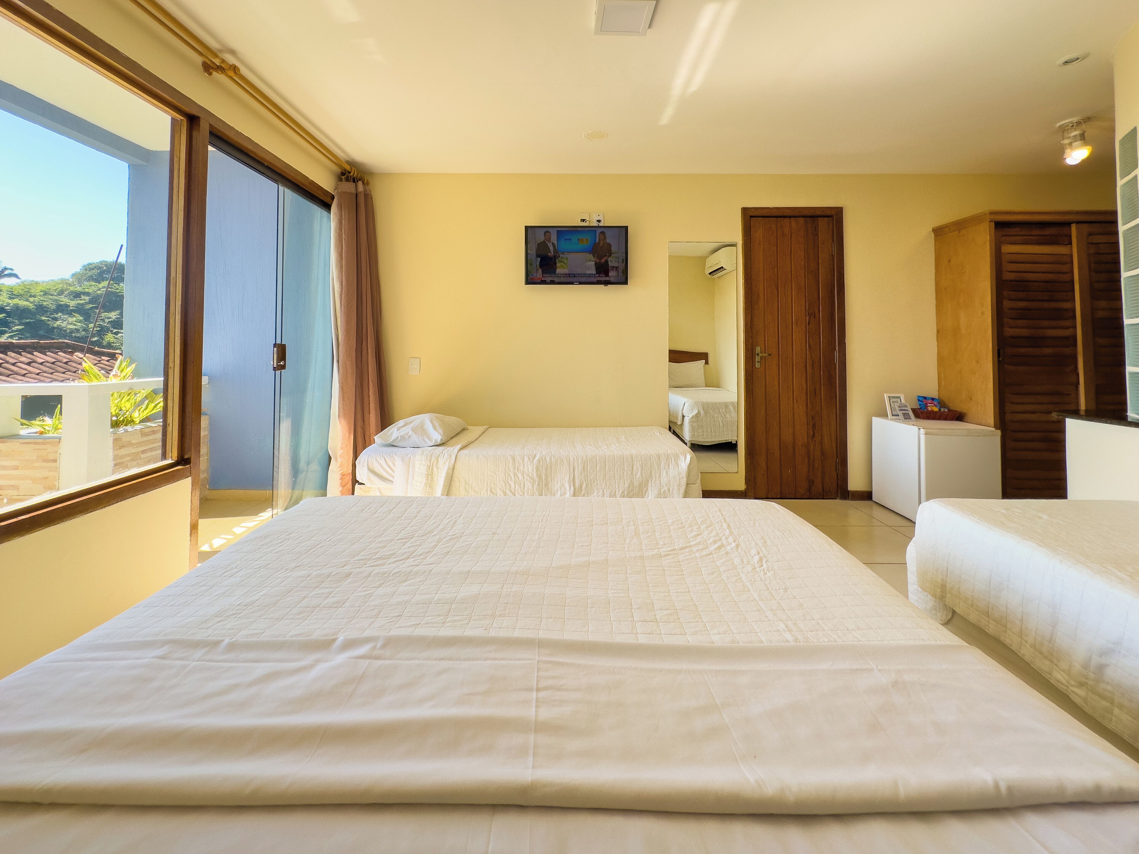 Een hotelkamer met twee bedden, een klein bureau, een spiegel en een raam met gordijnen.