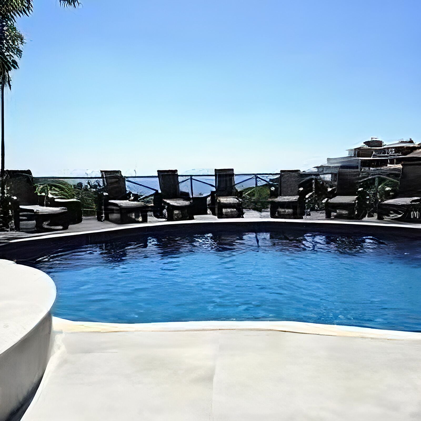 Zona de piscina con sillones de descanso y vista al océano.
